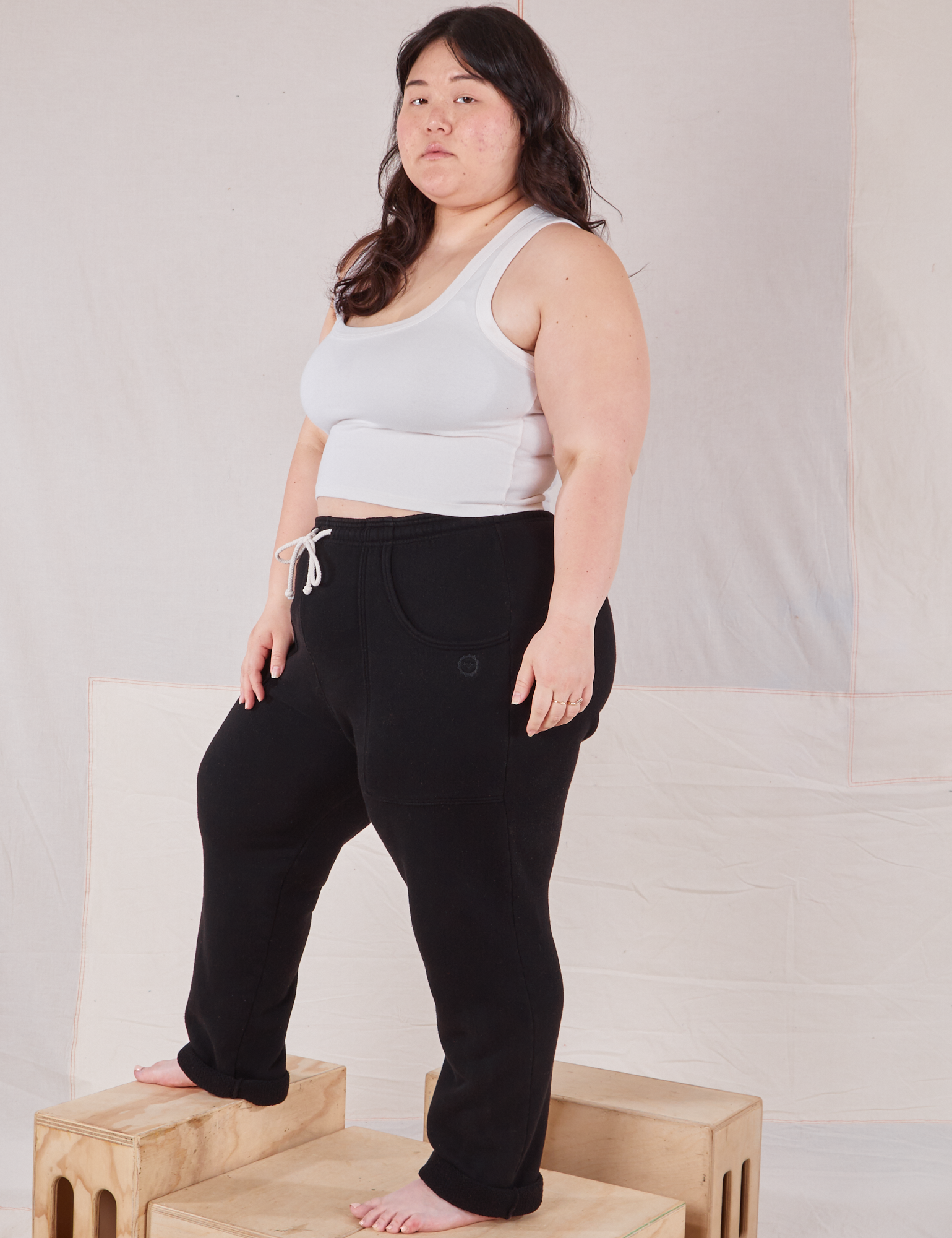 Angled front view of Rolled Cuff Sweat Pants in Basic Black and Cropped Tank in vintage tee off-white on Ashley