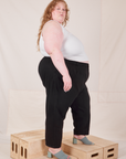 Side view of Heavyweight Trousers in Basic Black and Cropped Tank Top in vintage tee off-white worn by Catie.