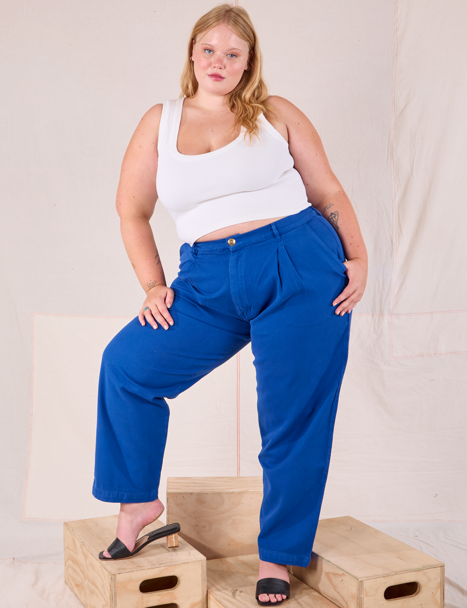 Juliet is 5’7” and wearing 0XL Heritage Trousers in Royal Blue paired with a Cropped Tank in vintage tee off-white