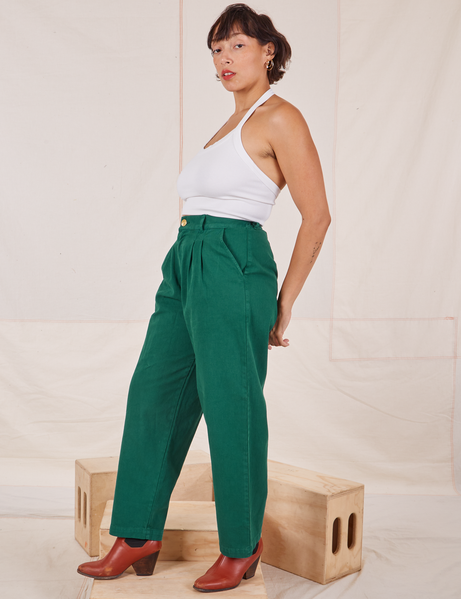 Side view of Heavyweight Trousers in Hunter Green and Halter Top in vintage in off-white worn by Tiara