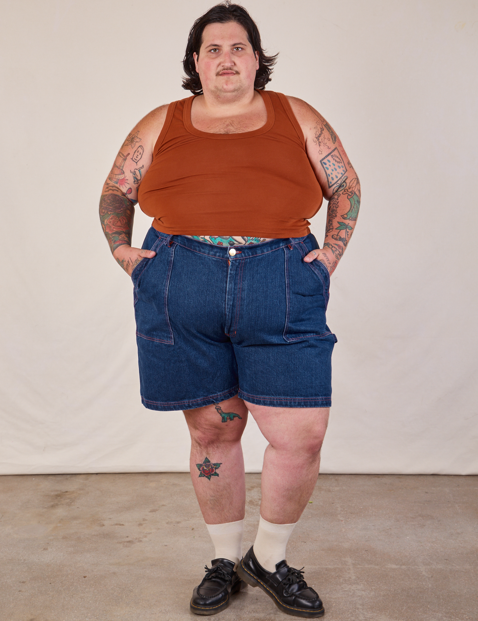 Sam is 5'10" and wearing 3XL Carpenter Shorts in Dark Wash paired with burnt terracotta Cropped Tank