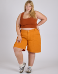Juliet is 5’7” and wearing 2XL Longline Work Shorts in Creamsicle Orange paired with burnt terracotta Cropped Tank
