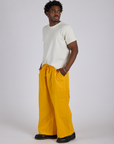Angled front view of Drop Pocket Cargo Pants in Sunshine Yellow and Organic Vintage Tee in Vintage Tee White on Isaac