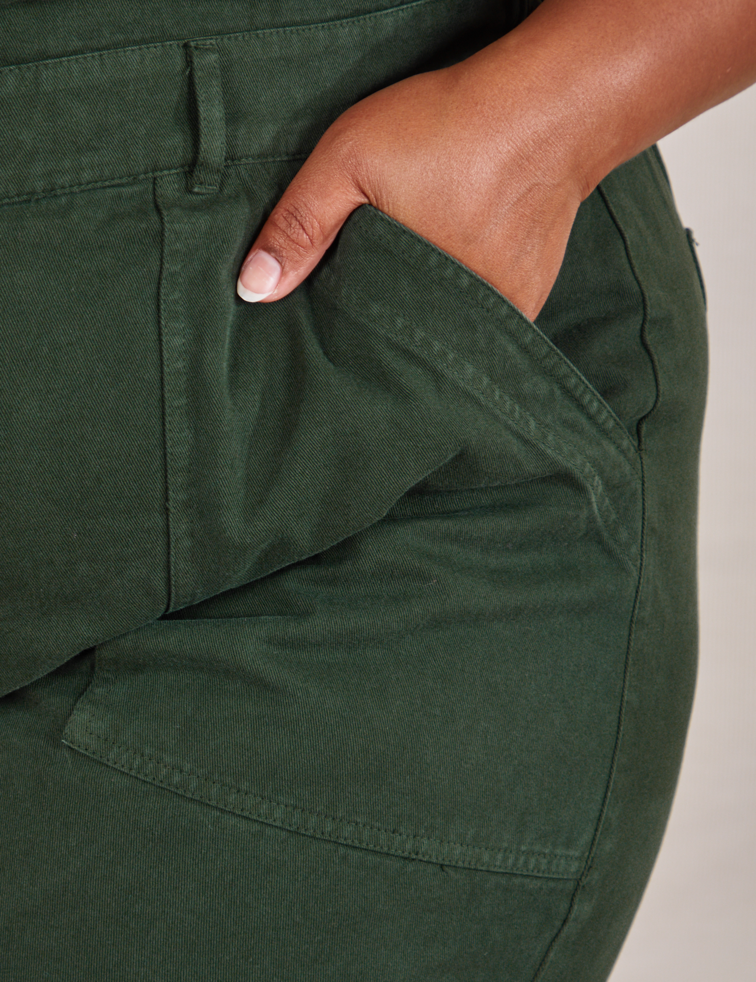 Short Sleeve Jumpsuit in Swamp Green front pocket close up. Morgan has her hand in the pocket.