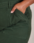 Short Sleeve Jumpsuit in Swamp Green front pocket close up. Morgan has her hand in the pocket.