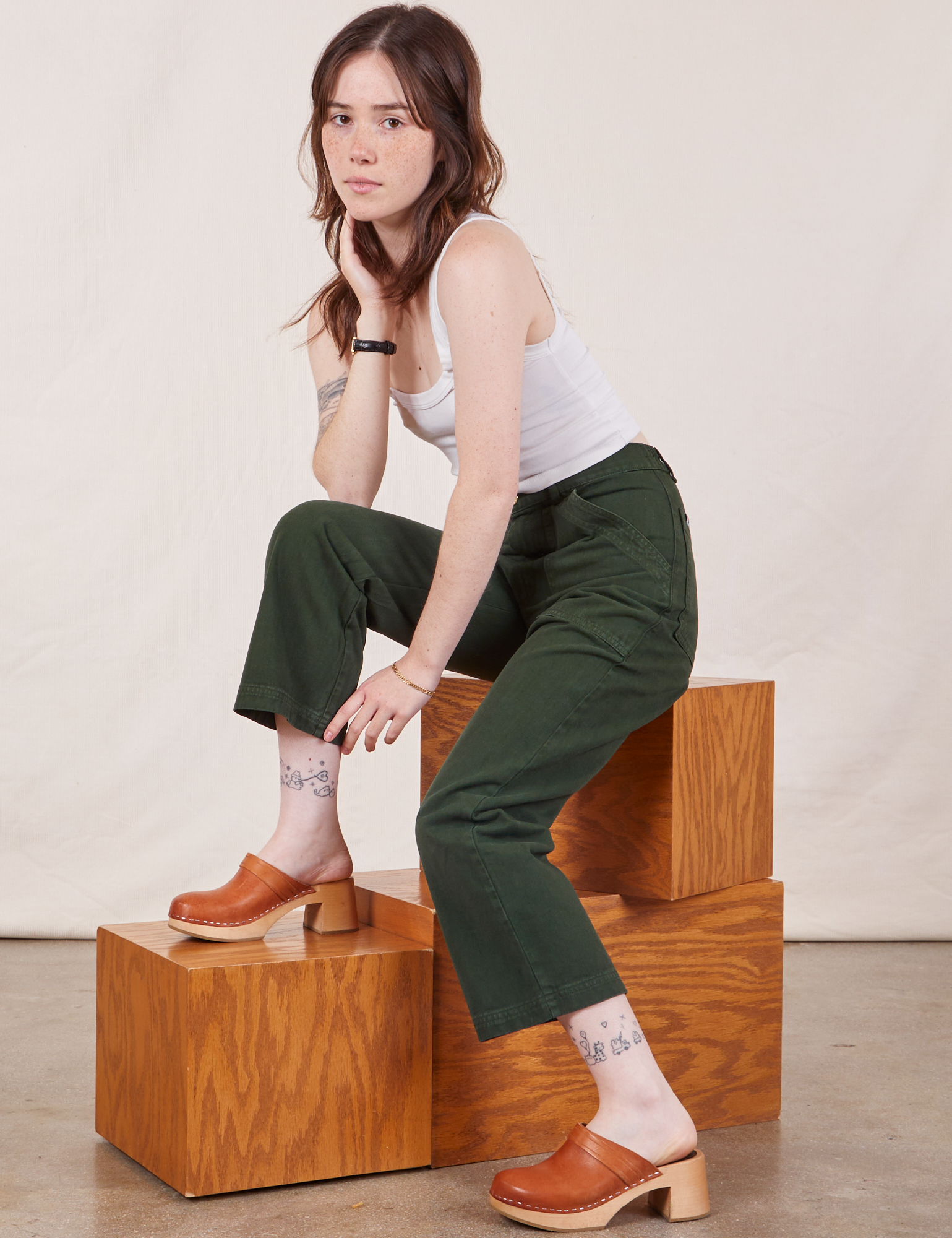 Hana is wearing Petite Work Pants in Swamp Green and Cropped Tank Top in vintage tee off-white