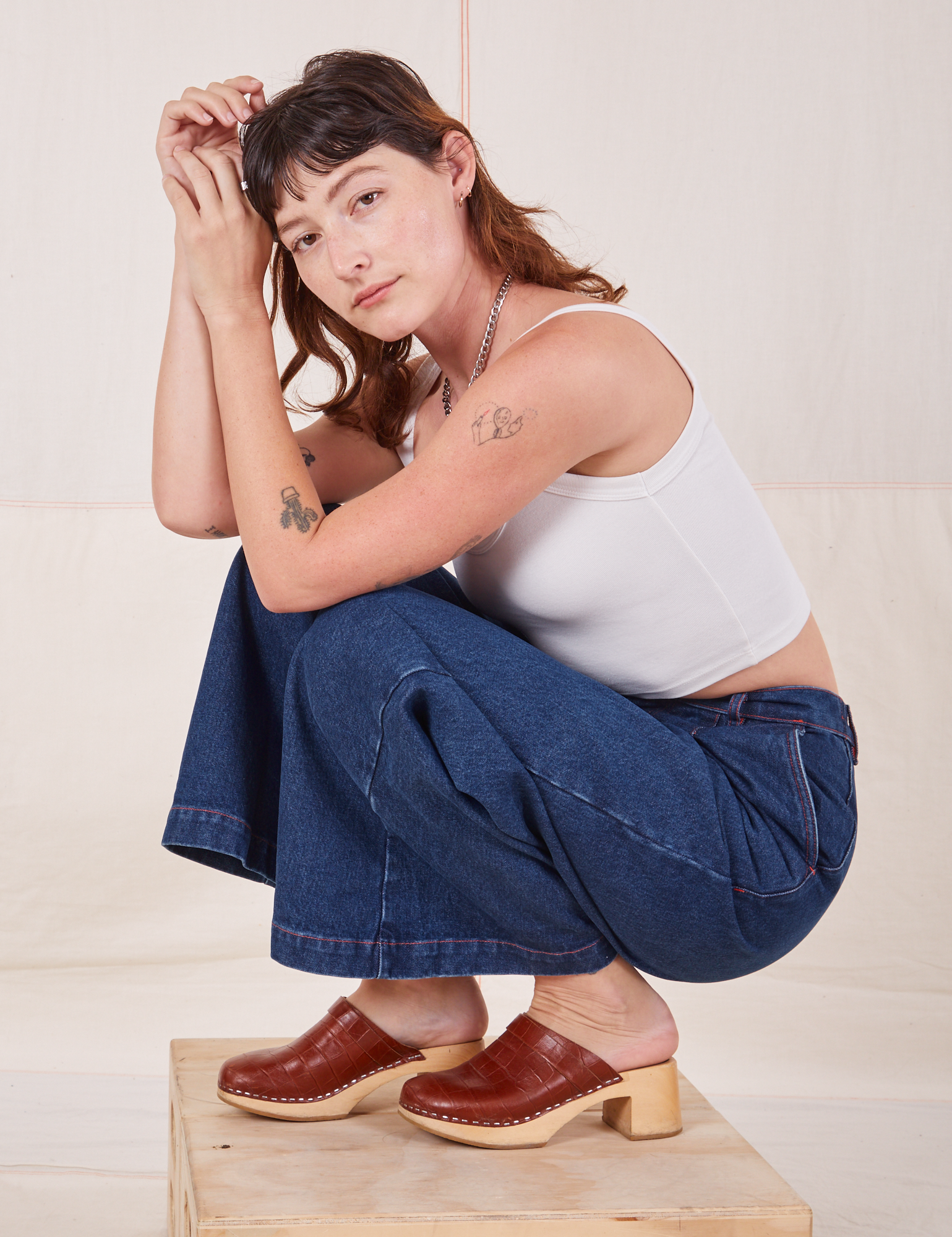 Alex is wearing Indigo Wide Leg Trousers in Dark Wash and vintage off-white Cami