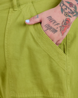 Close up of Sam's hand in the front pocket of Work Pants in Gross Green
