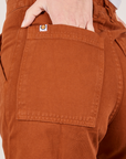 Classic Work Shorts in Burnt Terracotta back pocket close up. Madeline her hand in the pocket.
