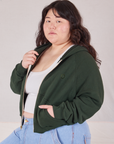 Angled front view of Cropped Zip Hoodie in Swamp Green and vintage off-white Cropped Tank on Ashley