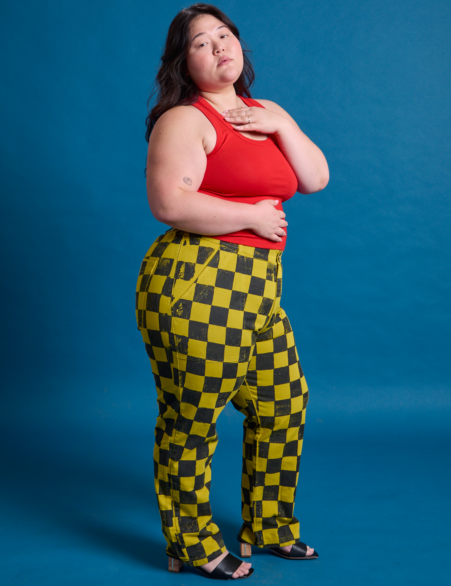 Side view of Checkerboard Work Pants in Yellow/Black and mustang red Tank Top on Ashley