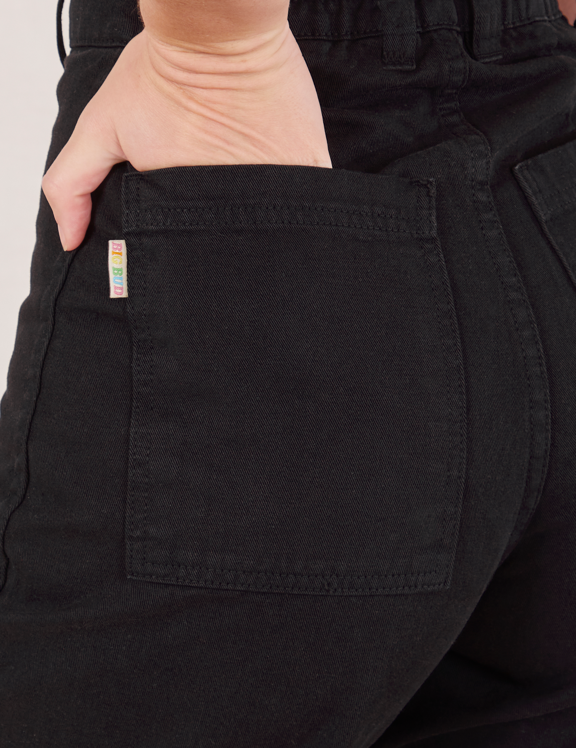 Bell Bottoms in Basic Black back pocket close up. Alex has her hand in the pocket.