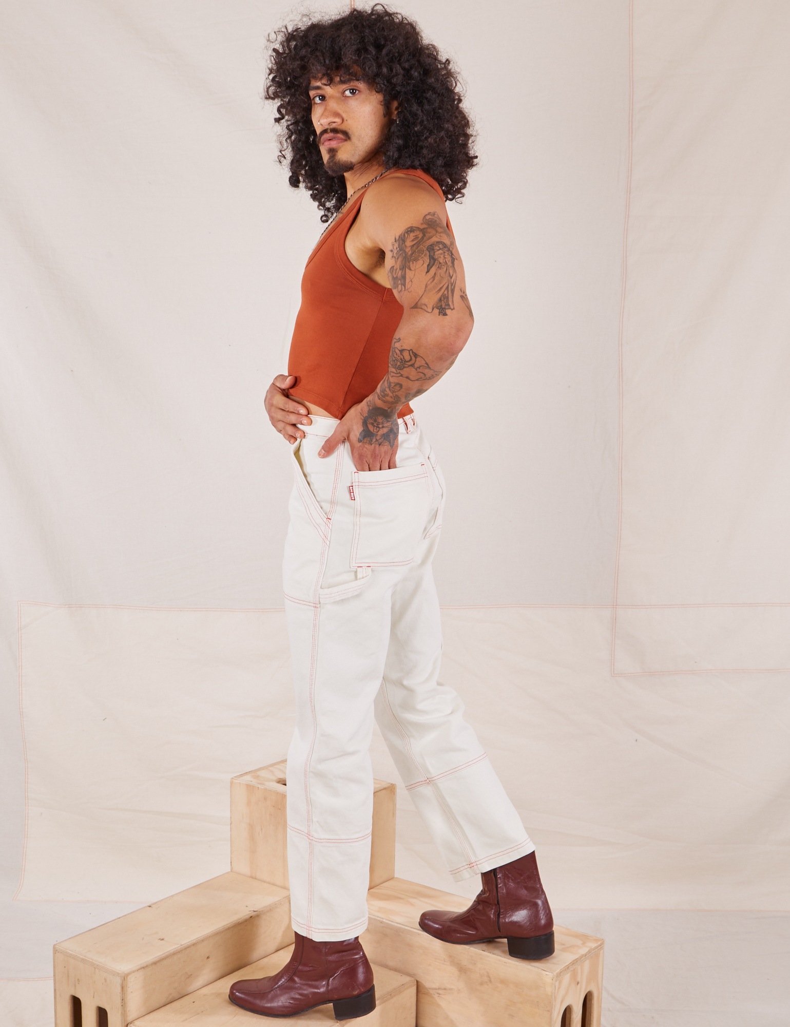 Side view of Carpenter Jeans in Vintage Off-White and burnt terracotta Cropped Tank Top on Jesse