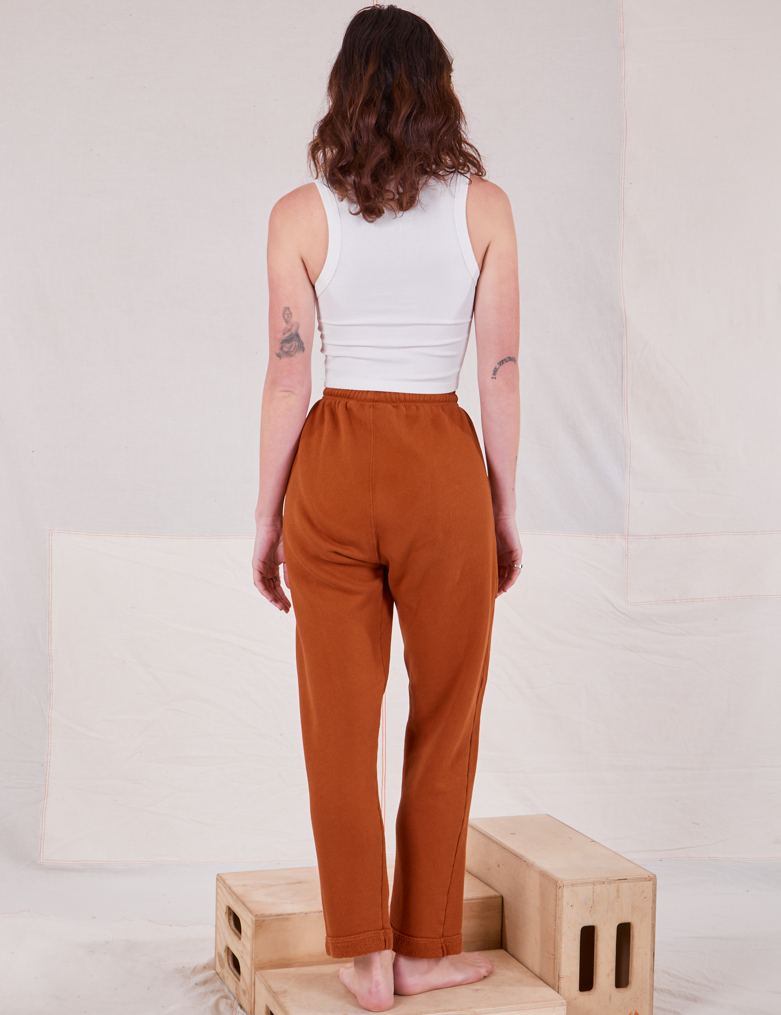 Back view of Rolled Cuff Sweat Pants in Burnt Terracotta and vintage off-white Cropped Tank on Alex