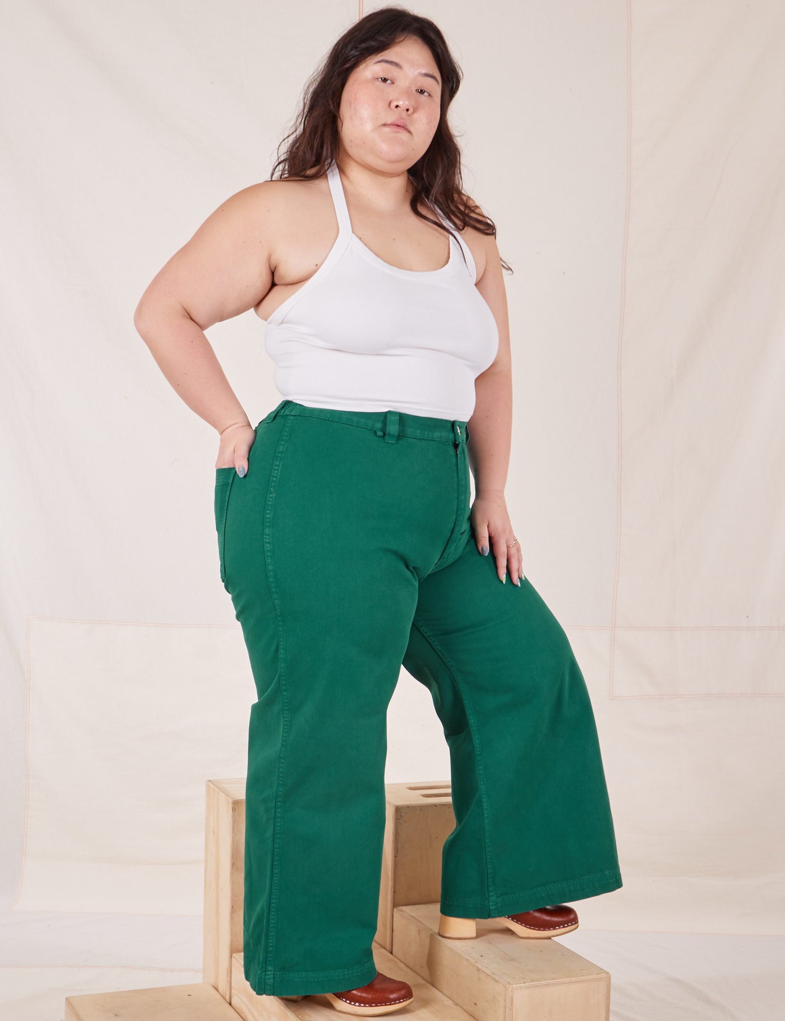 Angled view of Bell Bottoms in Hunter Green and Halter Top in vintage tee off-white worn by Ashley