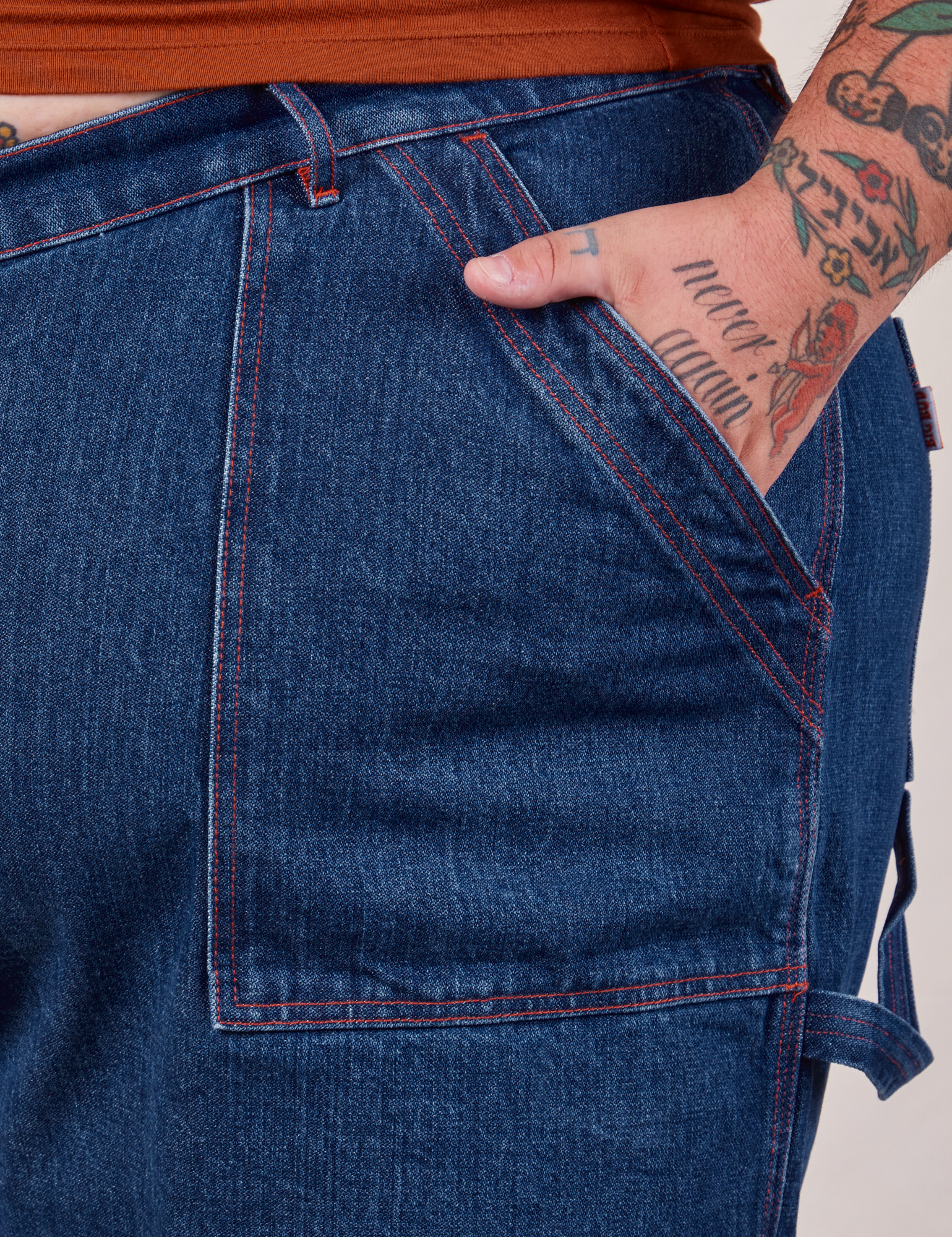 Carpenter Shorts in Dark Wash front pocket close up. Sam has their hand in the pocket.