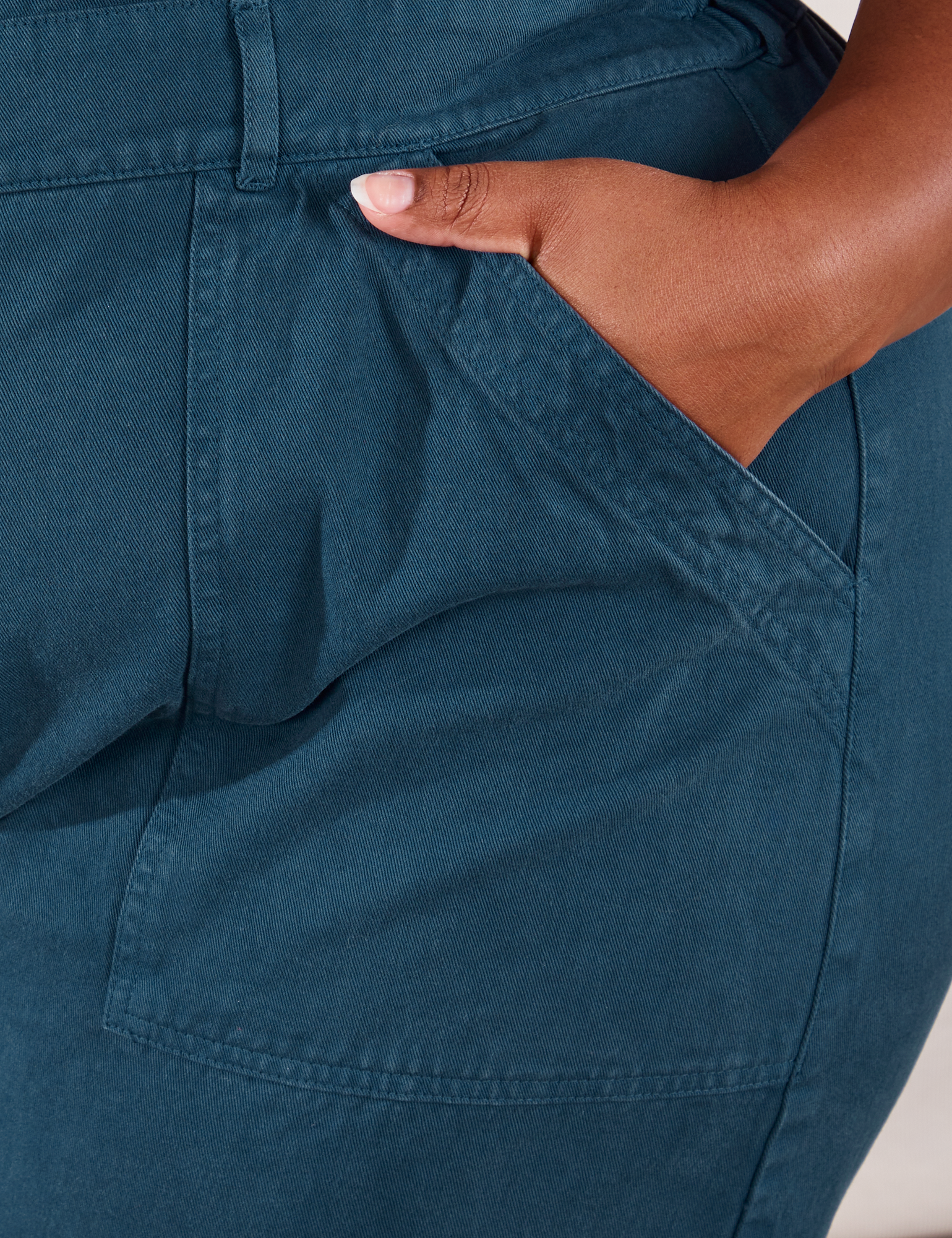 Short Sleeve Jumpsuit in Lagoon front pocket close up. Morgan has her hand in the pocket.