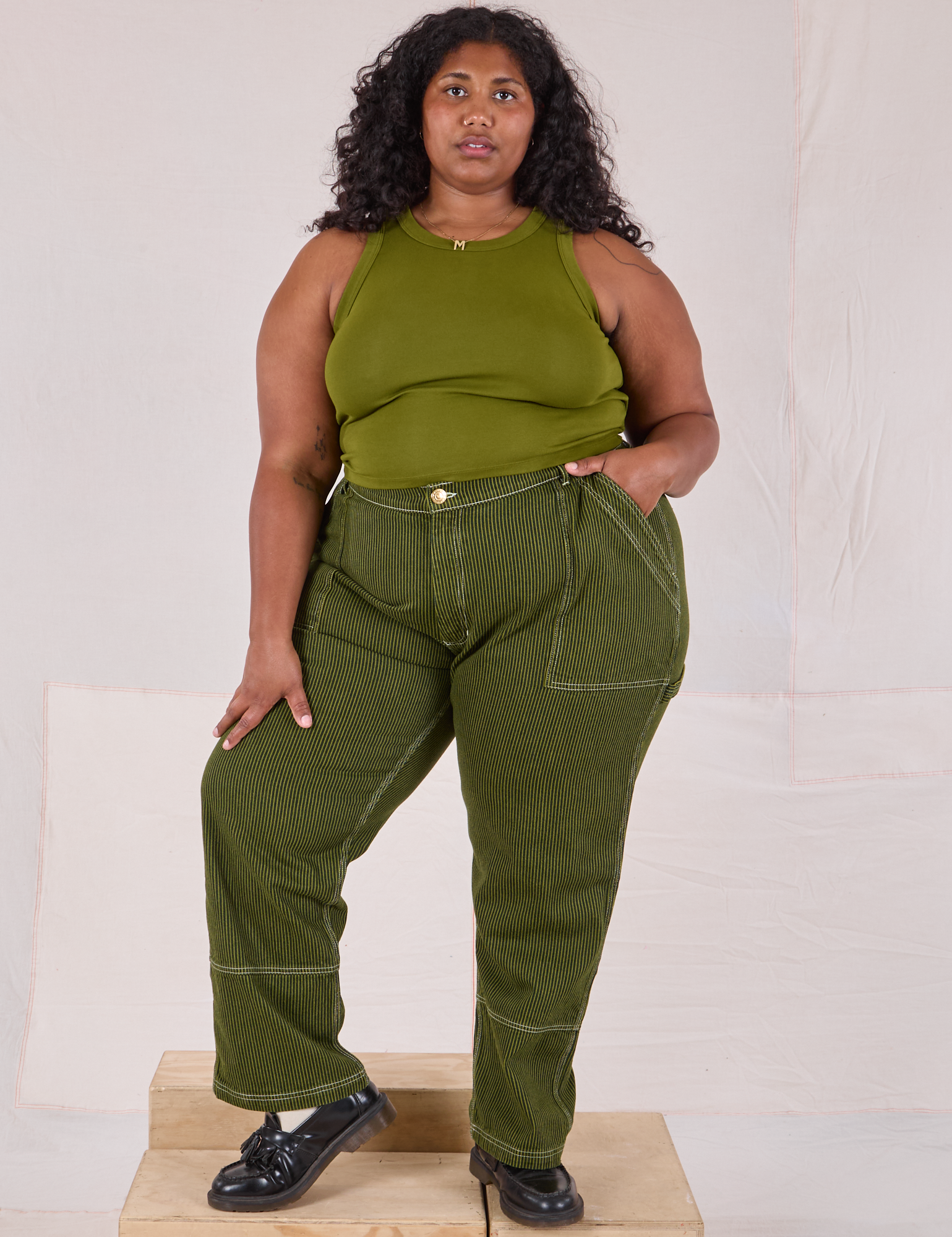 Morgan is 5’5’” and wearing 2XL Railroad Carpenter Jeans in Summer Olive and summer olive Muscle Tee