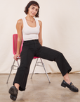 Soraya is sitting in a pink chair wearing Western Pants in Basic Black paired with Tank Top in vintage off-white