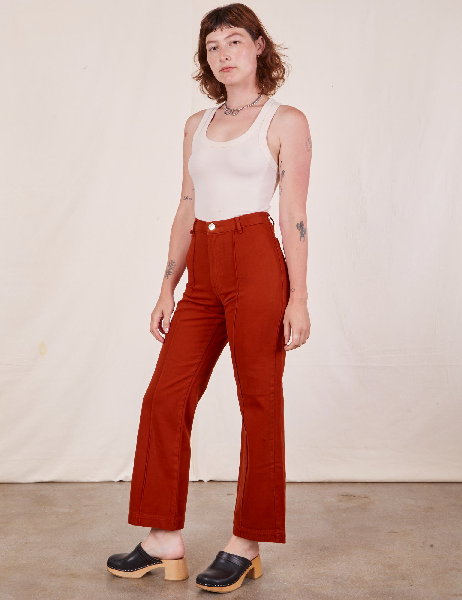 Angled view of Western Pants in Paprika and Tank Top in vintage tee off-white worn by Alex