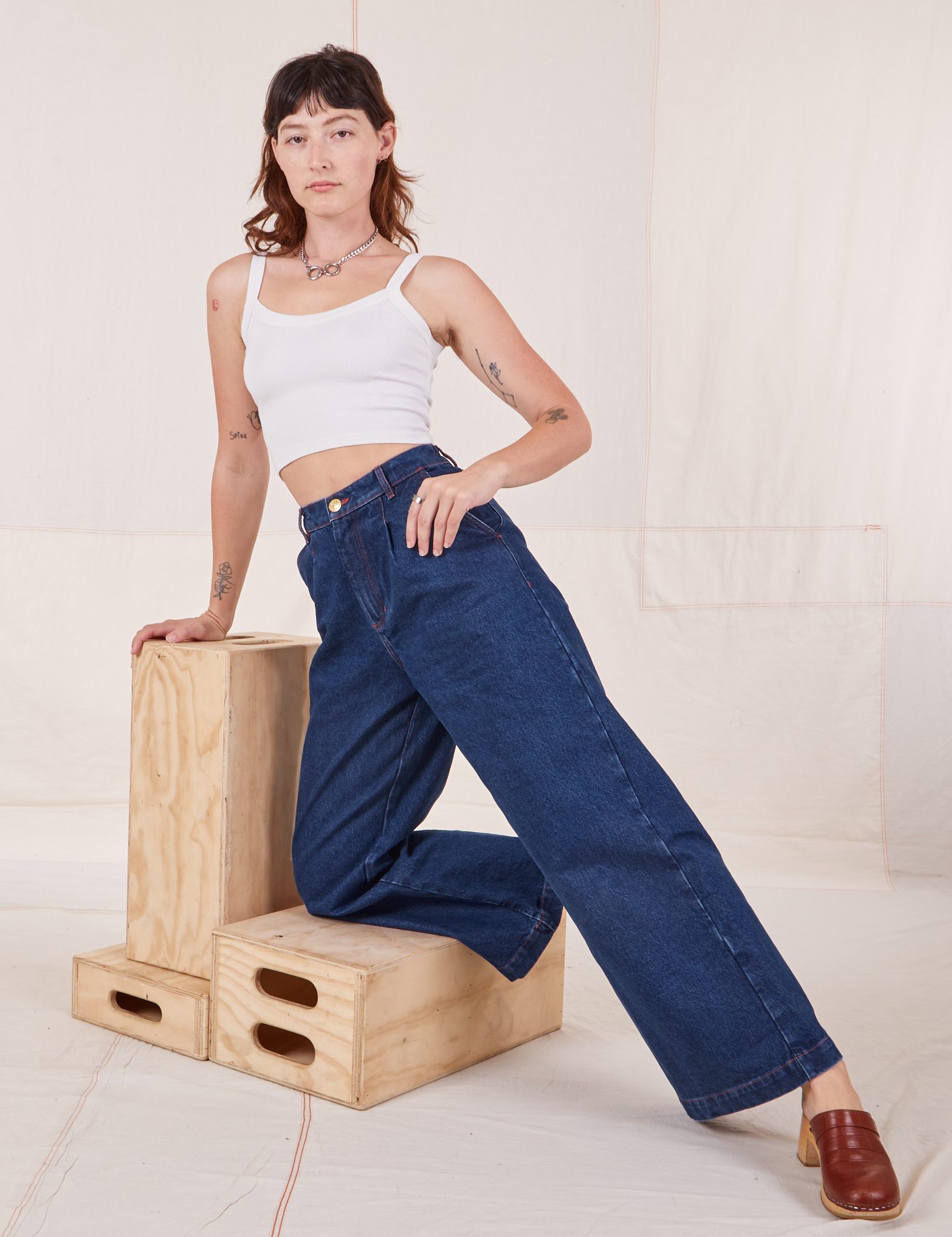 Alex is wearing Indigo Wide Leg Trousers in Dark Wash and vintage off-white Cami