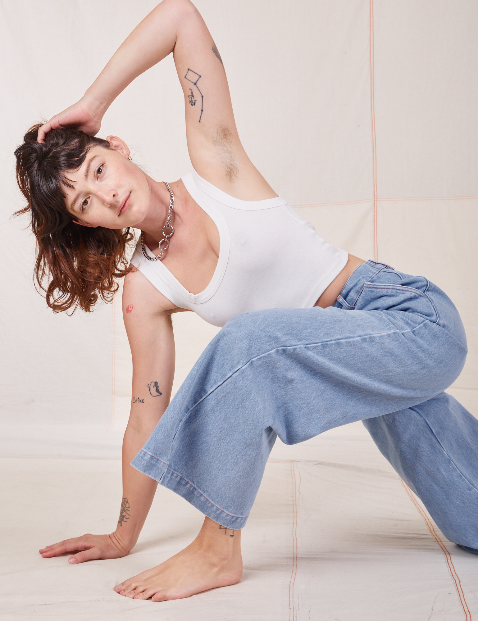 Alex is wearing Indigo Wide Leg Trousers in Light Wash and vintage off-white Cropped Tank Top
