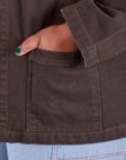 Close up of Morgan's hand in the front pocket of Denim Work Jacket in Espresso Brown