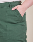 Front pocket close up of Work Pants in Dark Emerald Green. Worn by Ashley with hand in the pocket.