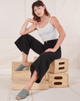 Alex is wearing Bell Bottoms in Basic Black and Cropped Cami in vintage tee off-white. She is sitting on a stack of wooden crates.