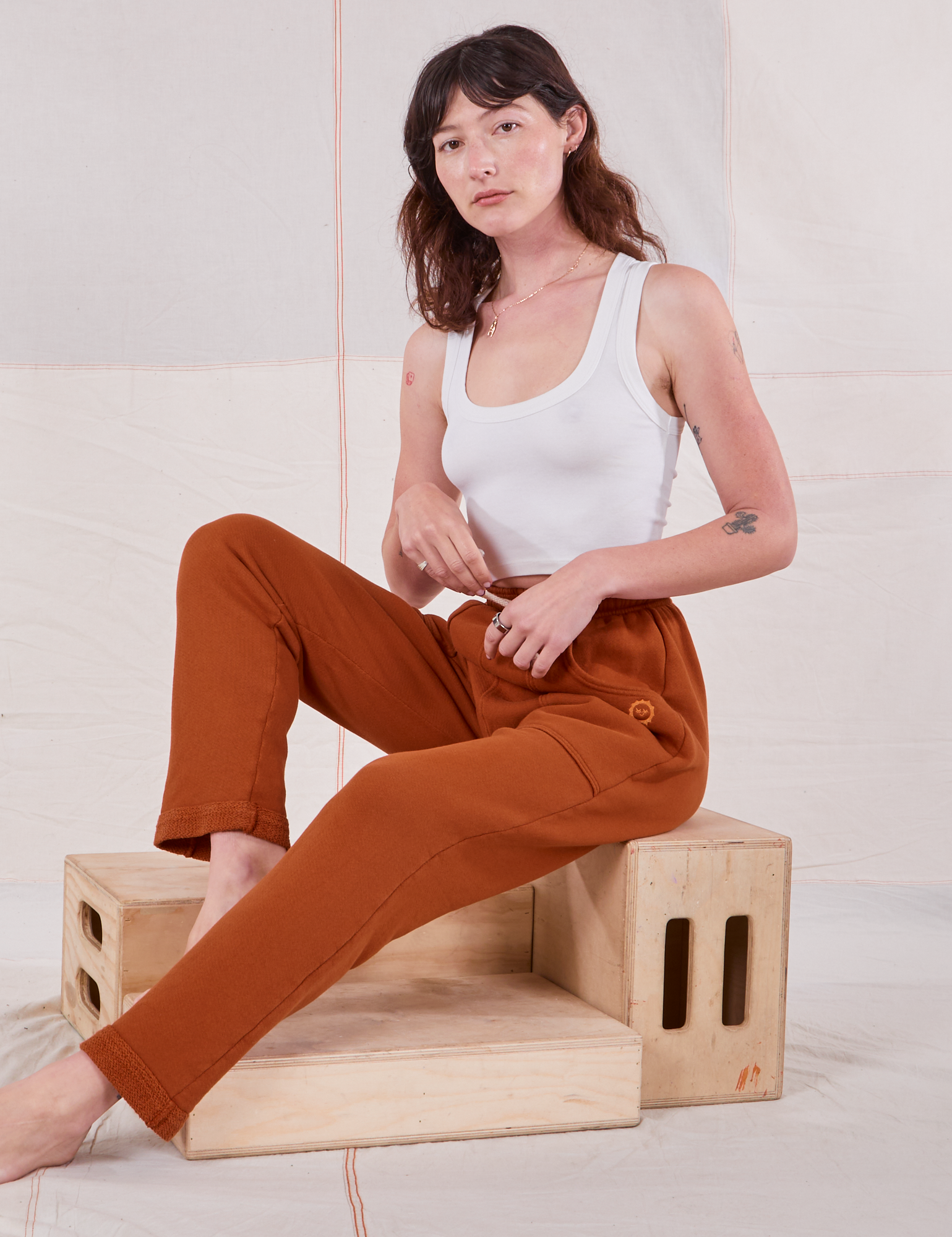 Alex is wearing Rolled Cuff Sweat Pants in Burnt Terracotta and vintage off-white Cropped Tank