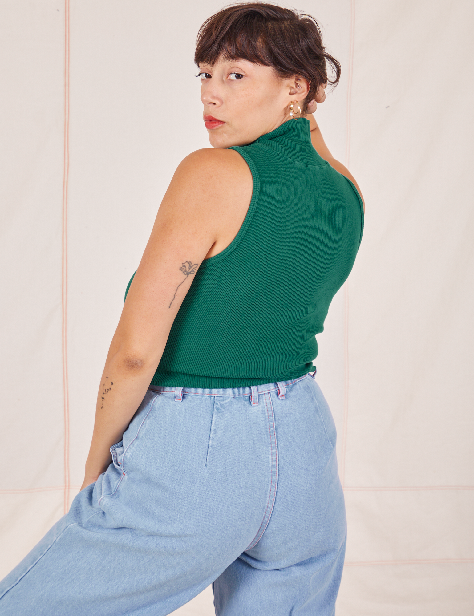 Angled back view of Sleeveless Essential Turtleneck in Hunter Green worn by Tiara