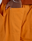 Close up of Isaac's hand in the back pocket of Drop Pocket Cargo Pants in Creamsicle Orange