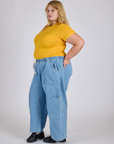 Side view of Jr. Varsity Tee in Sunshine Yellow tucked into light wash Denim Drop Pocket Pants