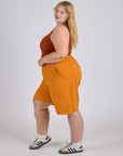 Side view of Longline Work Shorts in Creamsicle Orange and burnt terracotta Cropped Tank on Juliet