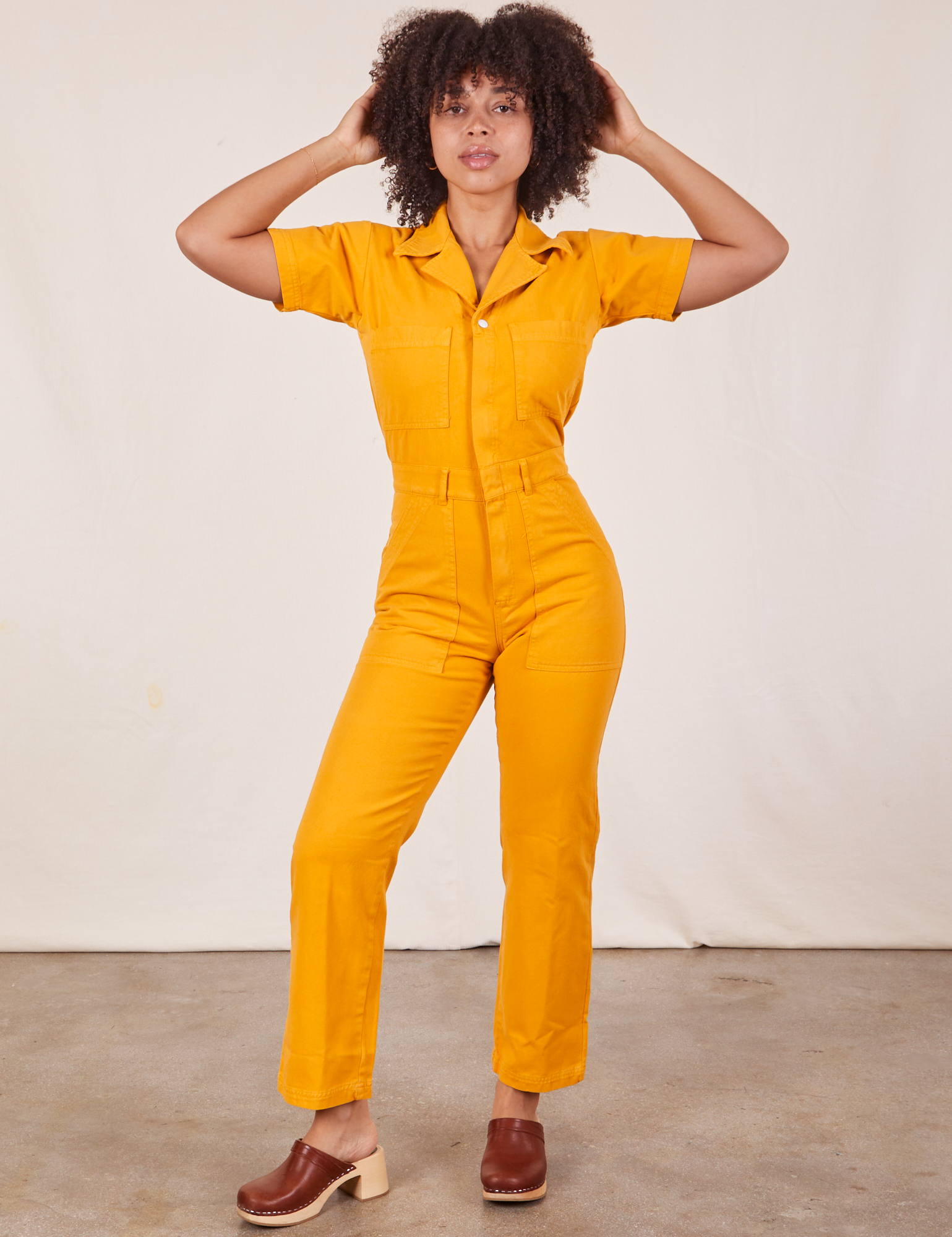 Gabi is 5&#39;7&quot; and wearing XS Short Sleeve Jumpsuit in Mustard Yellow
