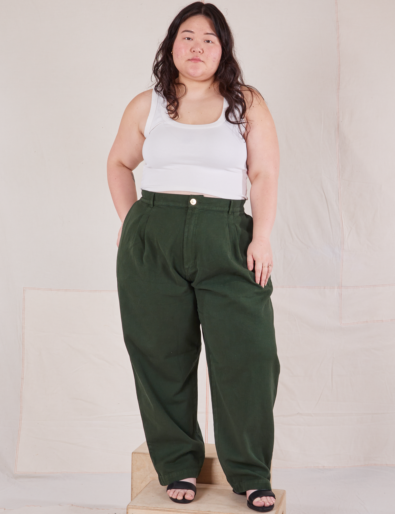 Ashley is 5&#39;7&quot; and wearing 1XL Heritage Trousers in Swamp Green and Cropped Tank Top in vintage tee off-white