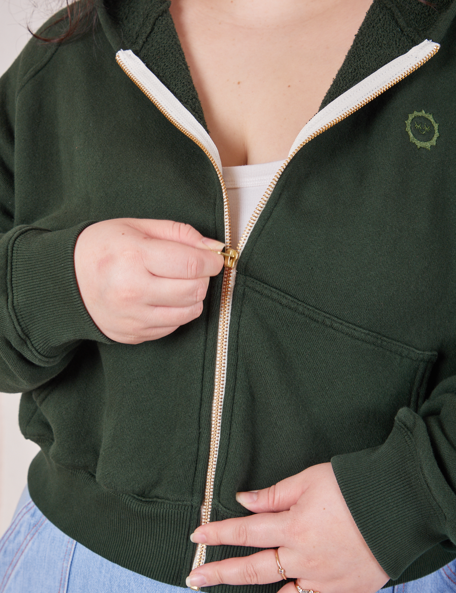 Cropped Zip Hoodie in Swamp Green front close up. Ashley is pulling the zipper up.