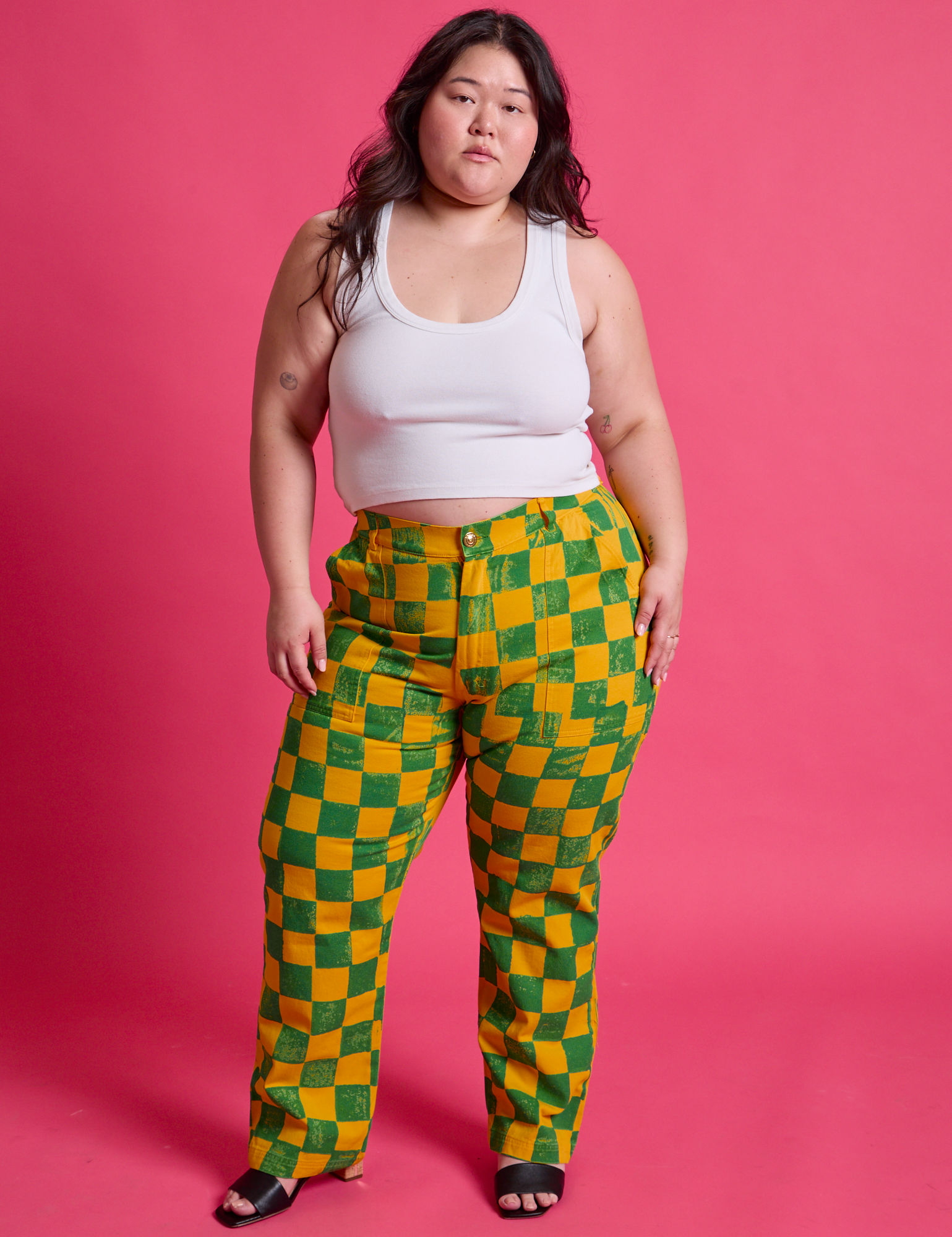Ashley is 5'7" and wearing 1XL Checkerboard Work Pants in Green/Yellow paired with a Cropped Tank in Vintage Tee White