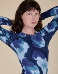 Angled front view of Long Sleeve Baby Tee in Blue Magic Waters on Alex