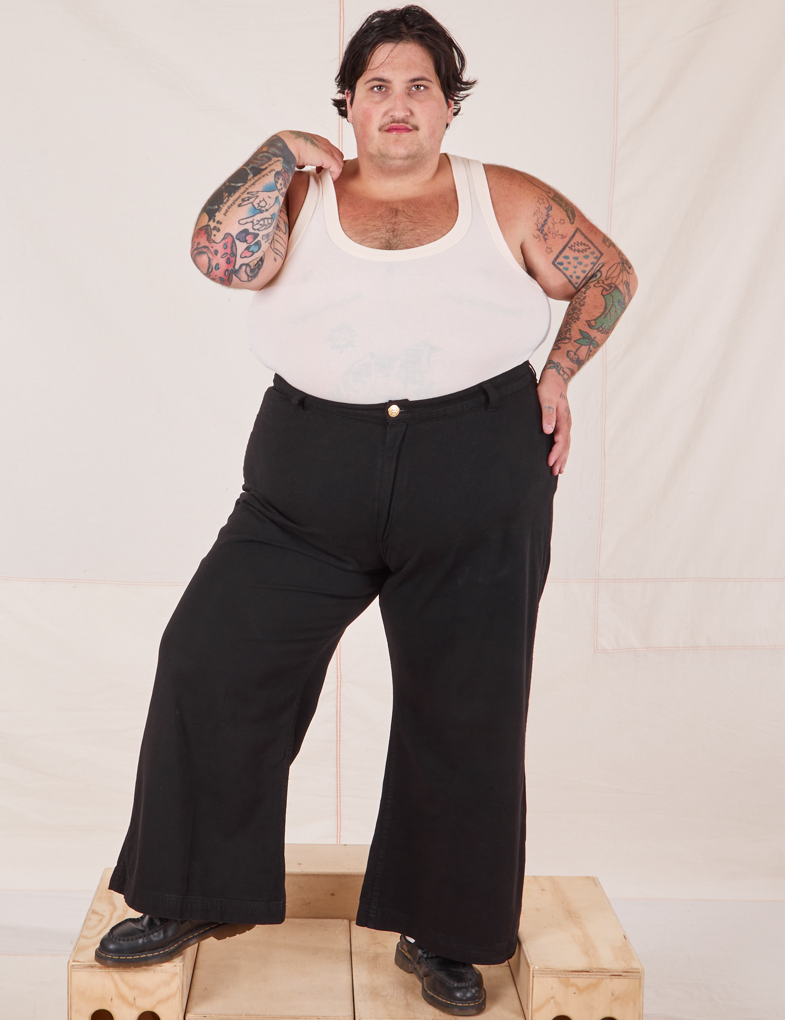 Sam is 5&#39;10&quot; and wearing 3XL Bell Bottoms in Basic Black paired with a Tank Top in vintage tee off-white