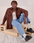 Isaac is wearing Flannel Overshirt in Fudgesicle Brown and light wash Carpenter Jeans