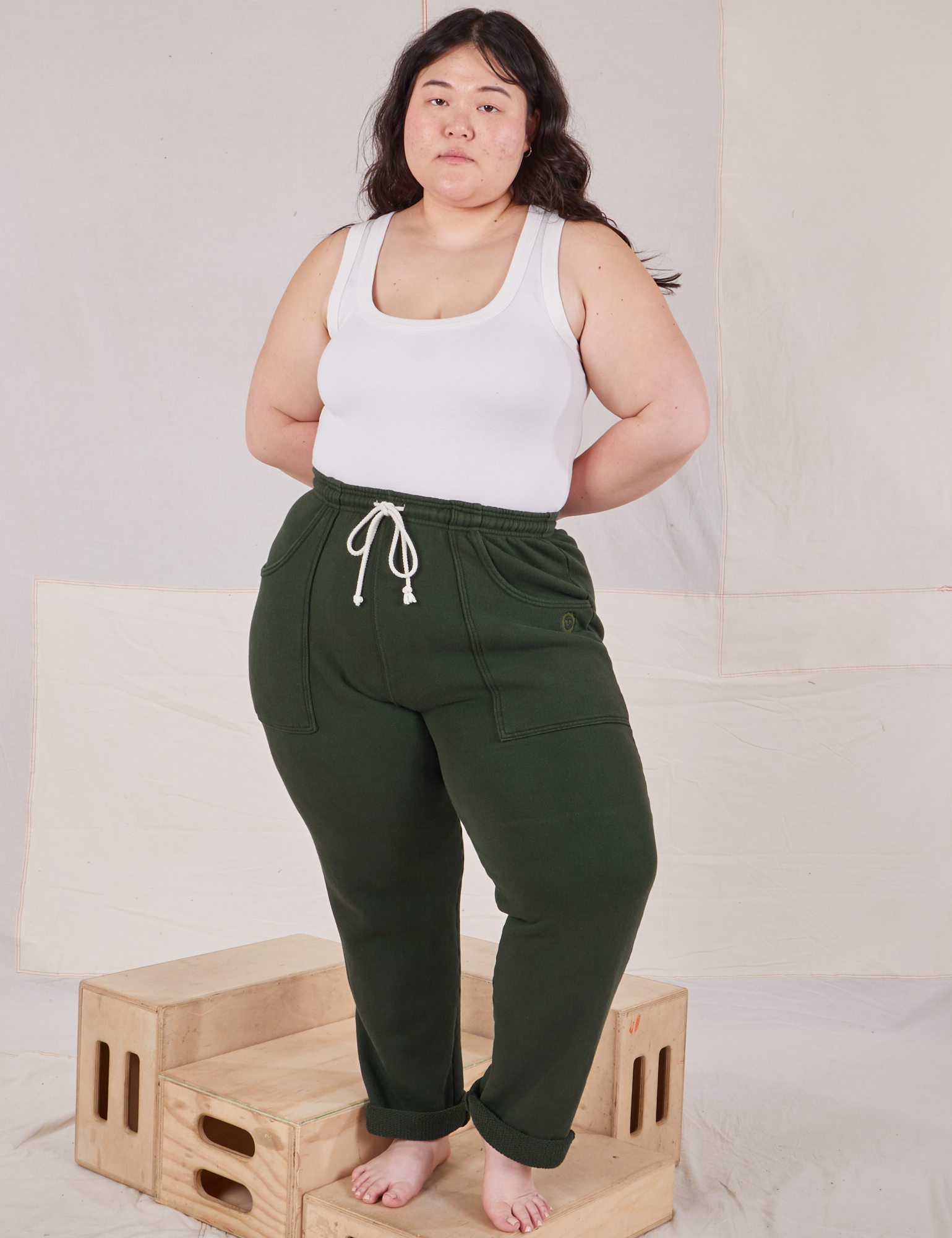 Ashley is 5&#39;7&quot; and wearing L Rolled Cuff Sweat Pants in Swamp Green and vintage off-white Cropped Tank