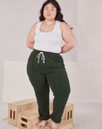 Ashley is 5'7" and wearing L Rolled Cuff Sweat Pants in Swamp Green and vintage off-white Cropped Tank