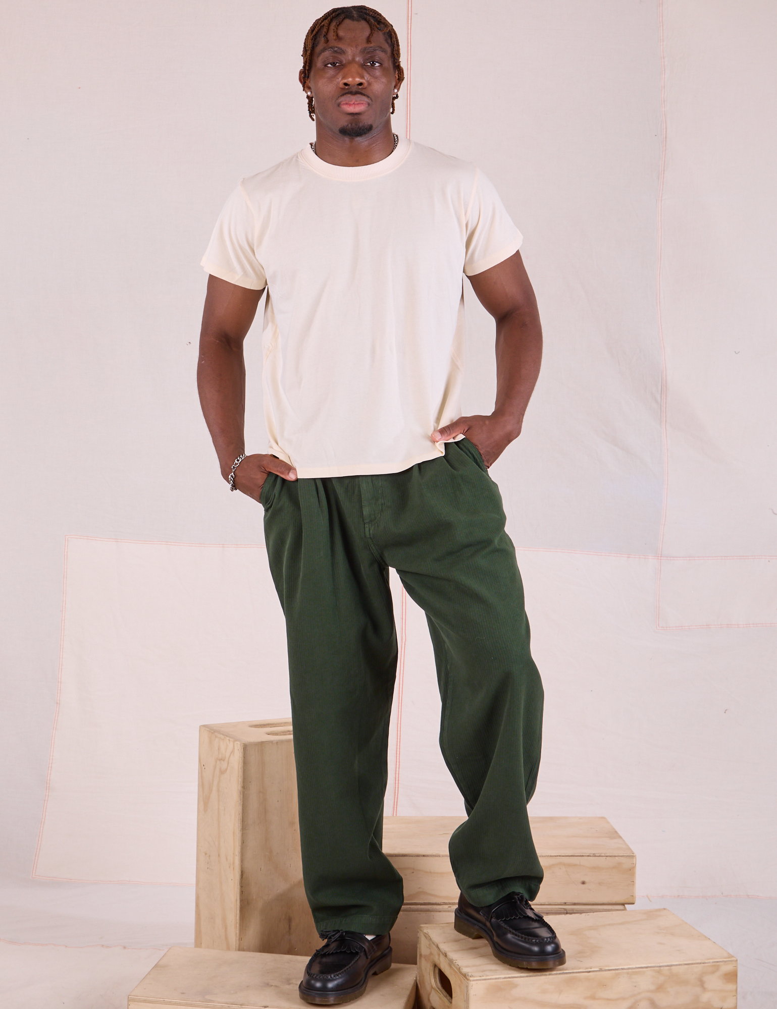 Issac 5’10” is and wearing M Heritage Trousers in Swamp Green paired with Organic Vintage Tee in vintage tee off-white