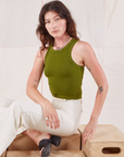 Alex is wearing Racerback Tank in Summer Olive and sitting on a crate