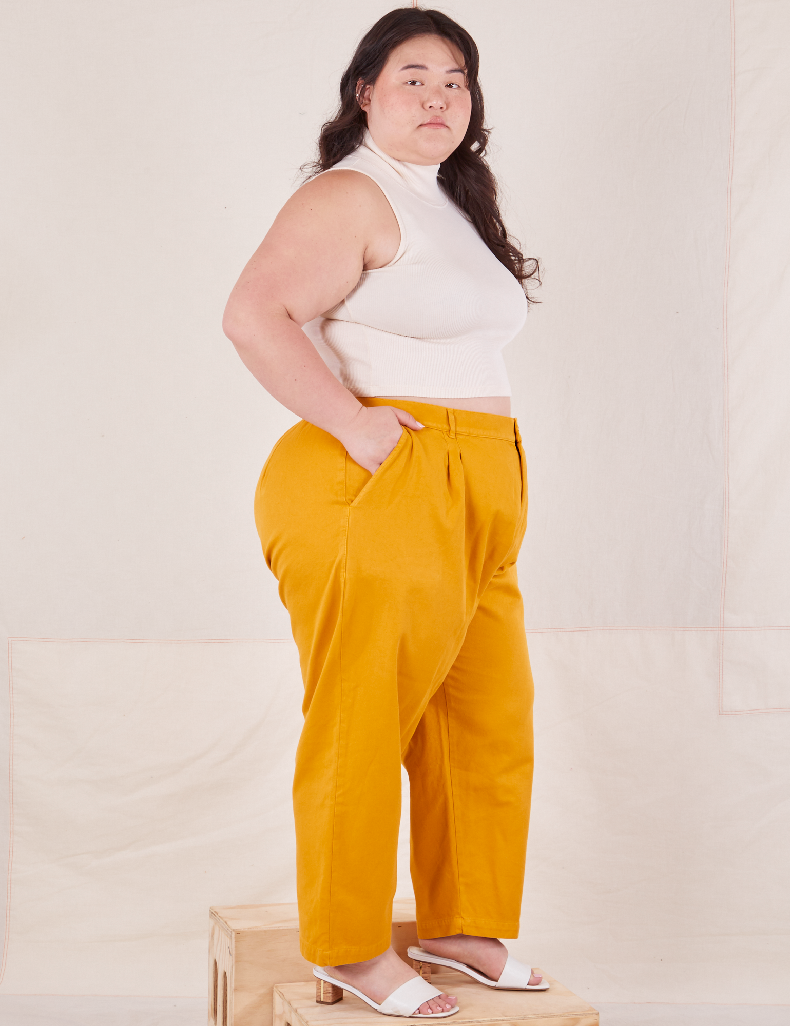 Side view of Organic Trousers in Mustard Yellow and Sleeveless Turtleneck in vintage tee off-white worn by Ashley