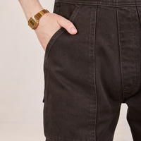 Front pocket close up of Original Overalls in Mono Espresso. Hana has her hand in the pocket.