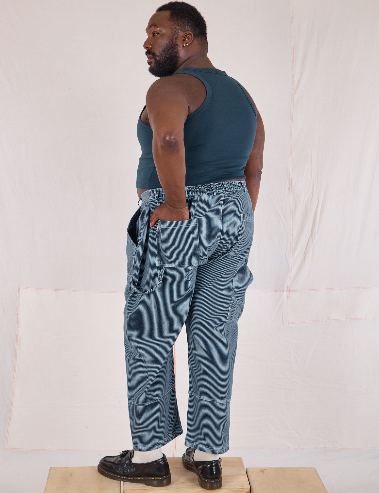 Angled back view of Railroad Carpenter Jeans in Baby Blue and marine blue Muscle Tee on Elijah