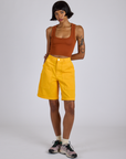 Kira is 5’10” and wearing XS Longline Work Shorts in Sunshine Yellow paired with burnt terracotta Cropped Tank