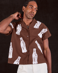 Jerrod is wearing a buttoned up Soda Bottle Pantry Button-Up in Fudgesicle Brown